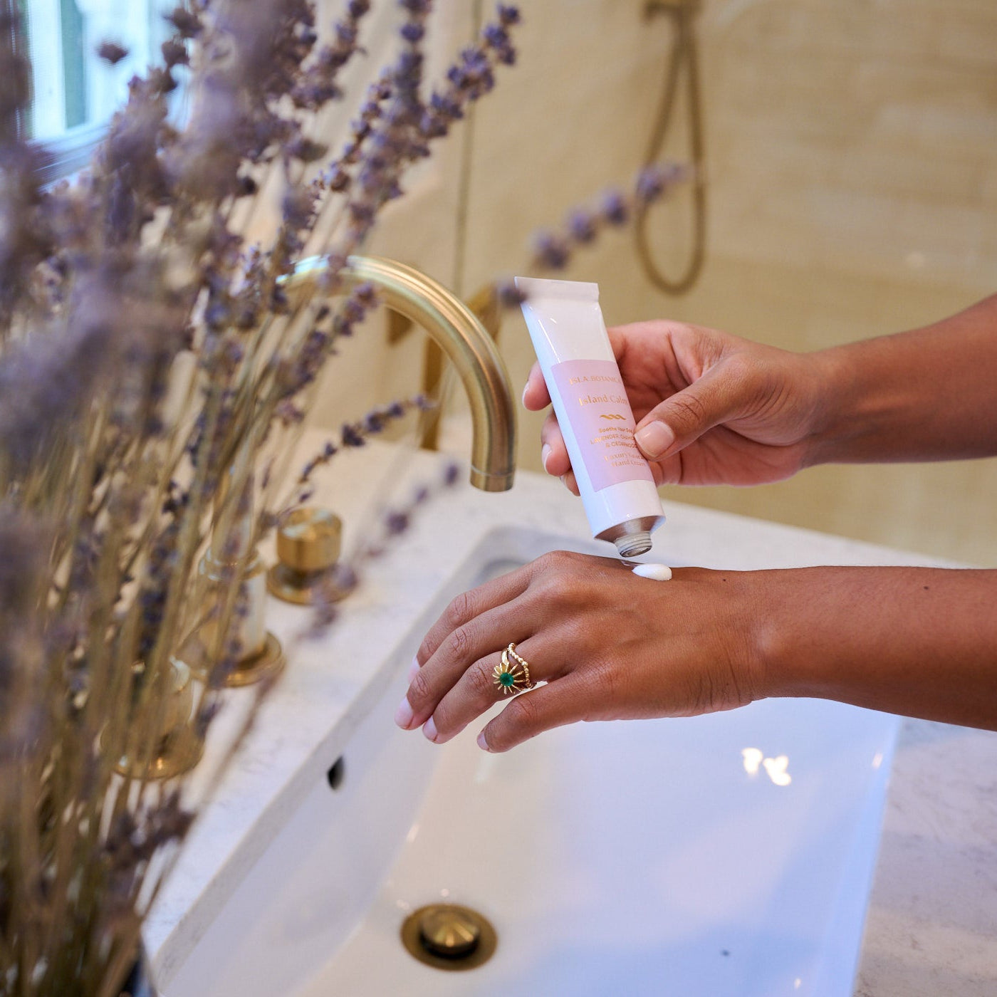Person washing hands with soap in a bathroom setting with lavender plants.